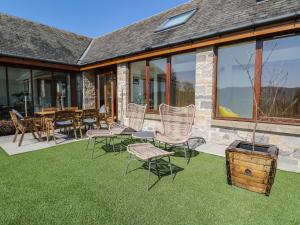 a patio with chairs and a table and a table and windows at Balvaig in Pitlochry