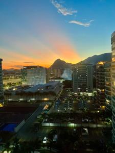 uma vista de uma cidade ao pôr do sol com carros num parque de estacionamento em Barra da Tijuca Depto decorado en Exclusivo Resort no Rio de Janeiro