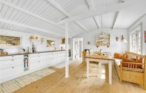 Bjerregårdにある2 Bedroom Cozy Home In Hvide Sandeの白いキャビネットと木製テーブル付きのキッチン