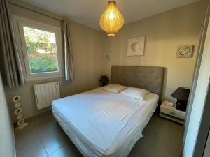 sypialnia z białym łóżkiem i oknem w obiekcie Appartement rénové 2 chambres avec piscine et tennis à La Croix Valmer - FR-1-726-12 w mieście La Croix-Valmer