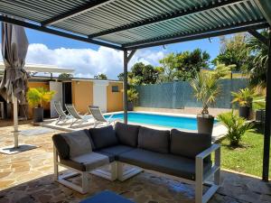 eine Terrasse mit einem Sofa und einem Pool in der Unterkunft Villa bassin bleu in Gourbeyre