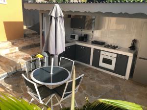 uma cozinha com uma mesa e cadeiras e um guarda-sol em Villa bassin bleu em Gourbeyre