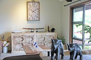 dwa posągi słoni na stole z zegarem na ścianie w obiekcie Riverview Lodge w mieście Hanmer Springs