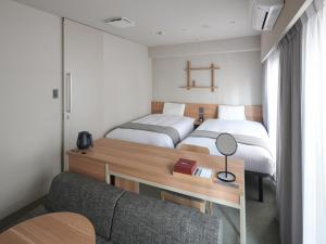 1 dormitorio con 2 camas y escritorio con sofá en Vessel Inn Asakusa Tsukuba Express, en Tokio