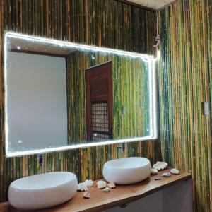 uma casa de banho com 2 lavatórios brancos e um espelho em Miley Lodging Restobar em New Busuanga