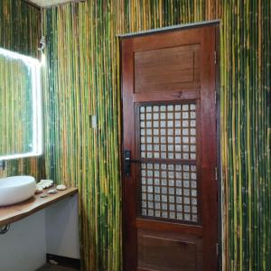 a bathroom with a wooden door and a sink at Miley Lodging Restobar in New Busuanga
