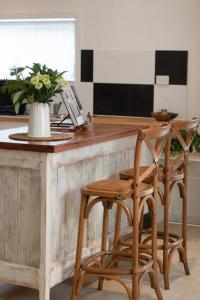 a kitchen with a counter with two chairs and a table at The Little House in Byron Bay