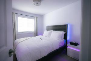 1 dormitorio con cama blanca con iluminación morada en 5 BEDS On The Rapids - 5 Mins To The Falls, en Niagara Falls