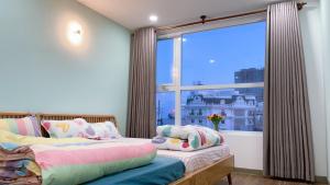 a bedroom with two beds and a large window at Vũng Tàu Apartmen OSC in Vung Tau