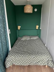 uma cama num quarto com uma parede verde em Studio cosy em Le Mée-sur-Seine