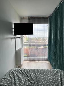 um quarto com uma cama e uma grande janela em Studio cosy em Le Mée-sur-Seine