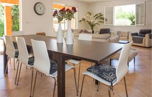 a dining room table with white chairs and vases with flowers at Awesome Home In Bdarieux With Wifi, Private Swimming Pool And Outdoor Swimming Pool in Bédarieux