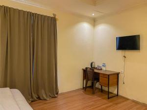 Zimmer mit einem Schreibtisch, einem Bett und einem TV in der Unterkunft Urbanview Hotel ME Jayapura in Jayapura