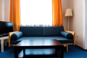 uma sala de estar com um sofá azul e uma mesa em Comfort Hotel em Aksay