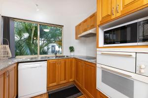 a kitchen with wooden cabinets and a microwave at Haven Waters 3 in Forster