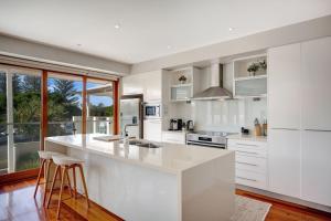 a kitchen with white cabinets and a large island at 2 20 Kingfisher Dr Peregian Beach in Peregian Beach