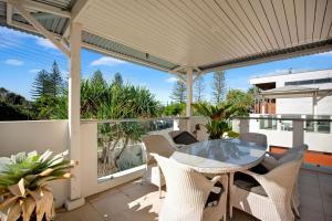 a patio with a table and chairs on a balcony at 2 20 Kingfisher Dr Peregian Beach in Peregian Beach