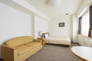 ein Hotelzimmer mit einem Bett, einem Sofa und einem Tisch in der Unterkunft Forest Hongo by unito in Tokio