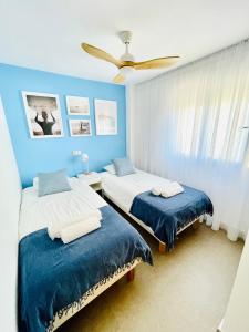 a bedroom with two beds and a ceiling fan at Apartamento Rokita Blanca in La Manga del Mar Menor