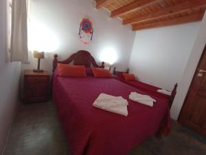 een slaapkamer met een rood bed en 2 handdoeken erop bij EL WICHIKU RECIDENCIAL - RESTO-BAR Facebook Hospedaje El Wichiku- Iruya in Iruya