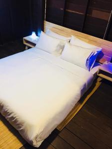 uma cama grande com lençóis brancos e almofadas em บ้านน่านโฮมสเตย์ em Nan