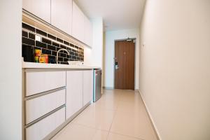 a kitchen with white cabinets and a hallway with a door at Chill Suites Kuala Lumpur in Kuala Lumpur