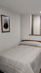 uma cama branca num quarto com uma fotografia na parede em Dimora Forgione B&B - Pietrelcina em Pietrelcina