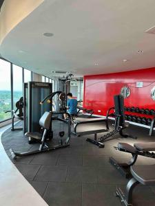 un gimnasio con equipo cardiovascular y pared roja en Cozy 2 BR Apartment w/ Pool Gym Wi-Fi & Work Space en Klang