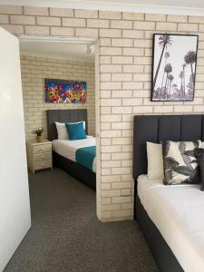 um quarto com 2 camas e uma parede de tijolos em Beach Park Motel 