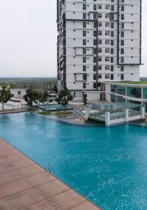 a large swimming pool in front of a tall building at Cozy 2 BR Apartment w/ Pool Gym Wi-Fi & Work Space in Klang
