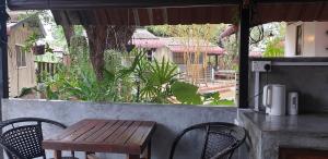 uma mesa de madeira e cadeiras em frente a uma janela em Bunga Hostel em Pantai Cenang