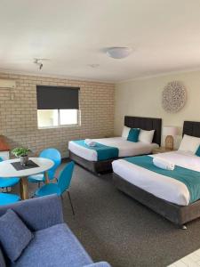 a hotel room with two beds and a table and chairs at Beach Park Motel in Gwynneville