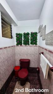 a bathroom with a red toilet and plants on the wall at Amaru Wasi in Cusco