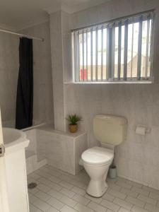 a bathroom with a toilet and a sink and a window at Beach Park Motel in Gwynneville