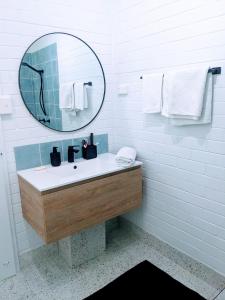 een witte badkamer met een wastafel en een spiegel bij Michaels by the Sea in Yeppoon