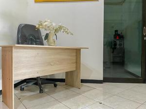 a wooden desk with a vase of flowers on it at Monalisa Homestay Mitra RedDoorz in Surabaya