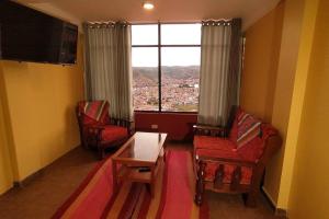 un soggiorno con due sedie, un tavolo e una finestra di Departamento amplio y panorámico a Cuzco