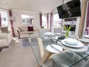 uma sala de estar com uma mesa de vidro e um sofá em Crosswinds 67 em Bembridge