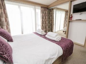 um quarto com uma cama grande e toalhas em Crosswinds 67 em Bembridge