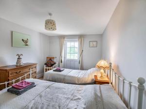 a bedroom with two beds and a dresser and a window at Orchard Barns in North Nibley