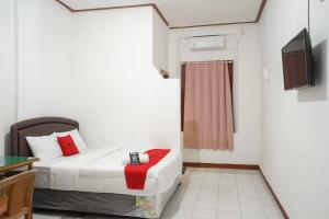 a small room with a bed and a television at RedDoorz Plus @ Alun Alun Nganjuk in Nganjuk