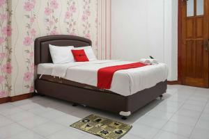a bedroom with a bed with a red blanket at RedDoorz Plus @ Alun Alun Nganjuk in Nganjuk