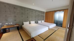 a bedroom with two white beds and a table and a window at Fu Wan Cafe Villa in Donggang