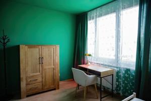 Grünes Zimmer mit einem Schreibtisch und einem Fenster in der Unterkunft Boho-Chic-Wohnung Neusiedl in Neusiedl am See