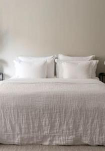 Una cama con sábanas blancas y almohadas. en Centrum lägenhet, en Skövde