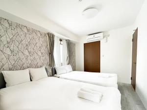 two beds in a hotel room with white walls at Dio Higashi Shinsaibashi in Osaka