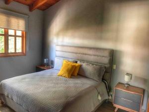 1 dormitorio con 1 cama con 2 almohadas amarillas en Cabaña Familiar 10 en Mazamitla
