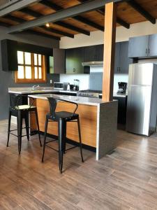馬薩米特拉鎮的住宿－Cabaña Familiar 10，厨房配有带椅子的柜台和冰箱。