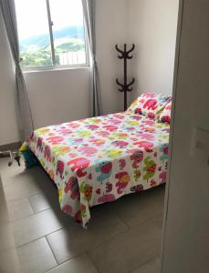 Un dormitorio con una cama con una manta de flores. en Casa Lucy, en Ibagué