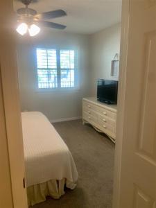 a bedroom with a bed and a television and a ceiling fan at 10 H Two Bedroom Condo in Destin